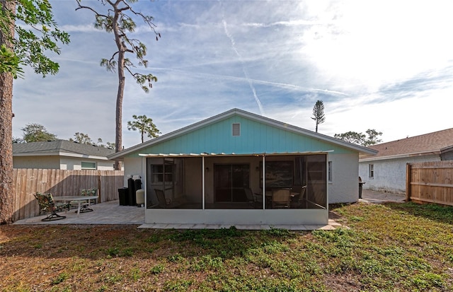 back of property with a patio, a sunroom, and a lawn