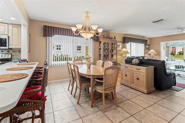 dining room featuring light tile patterned floors, ceiling fan with notable chandelier, and a textured ceiling