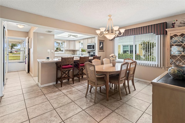 dining area with light tile patterned flooring, plenty of natural light, an inviting chandelier, and a textured ceiling