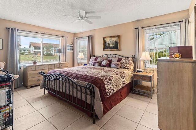 bedroom with multiple windows, light tile patterned floors, a textured ceiling, and ceiling fan