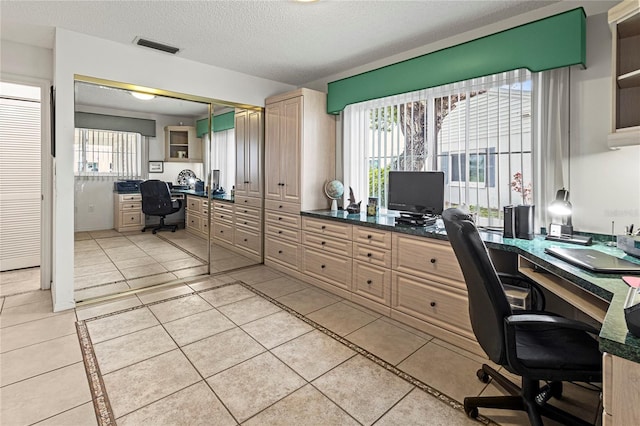 home office with built in desk, a textured ceiling, and light tile patterned floors