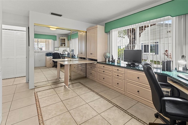 office featuring a wealth of natural light, light tile patterned floors, and a textured ceiling