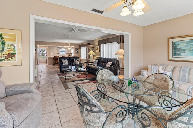 dining room featuring ceiling fan with notable chandelier, a textured ceiling, and light tile patterned floors