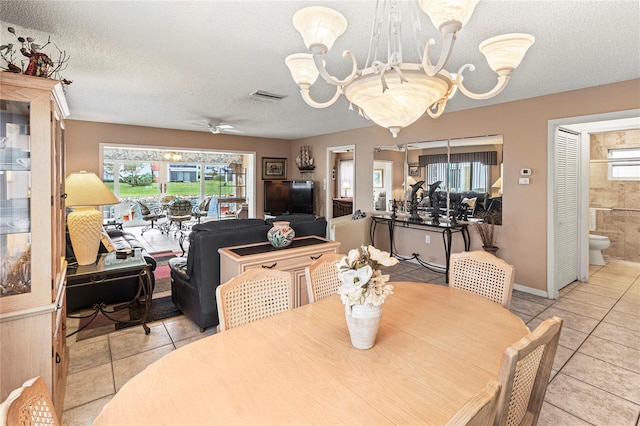 tiled dining area with ceiling fan with notable chandelier and a textured ceiling