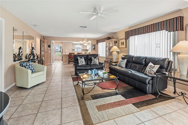 living room with light tile patterned flooring, ceiling fan with notable chandelier, and a textured ceiling