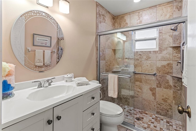 bathroom featuring vanity, toilet, and a shower with shower door