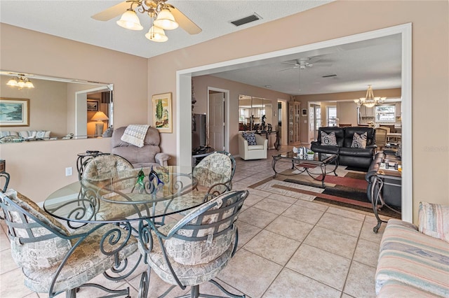 dining room featuring ceiling fan with notable chandelier, a textured ceiling, and light tile patterned floors