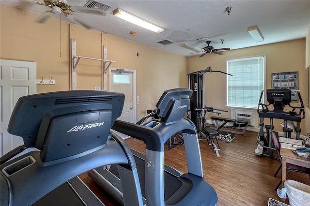 gym with a ceiling fan, visible vents, and wood finished floors