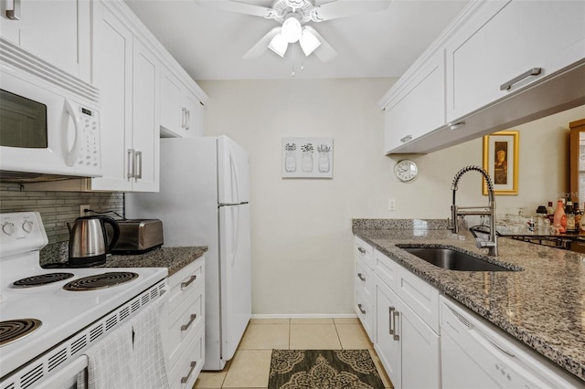 kitchen with white appliances, white cabinets, dark stone countertops, sink, and light tile patterned floors