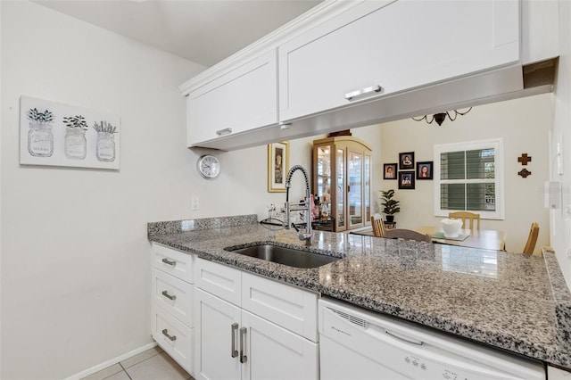 kitchen featuring white dishwasher, sink, white cabinetry, light tile patterned floors, and light stone counters