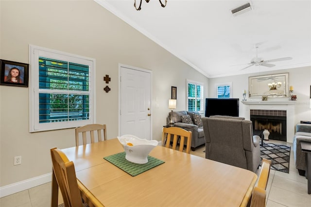 tiled dining room with ornamental molding, lofted ceiling, and a fireplace