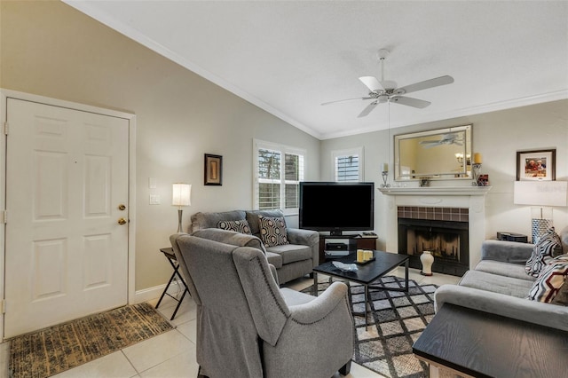 living room featuring lofted ceiling, a fireplace, ornamental molding, ceiling fan, and light tile patterned floors