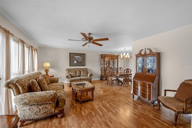 living room with ceiling fan with notable chandelier, a textured ceiling, and light hardwood / wood-style flooring