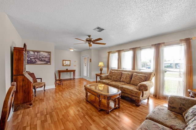 living room with ceiling fan, light hardwood / wood-style floors, and a textured ceiling