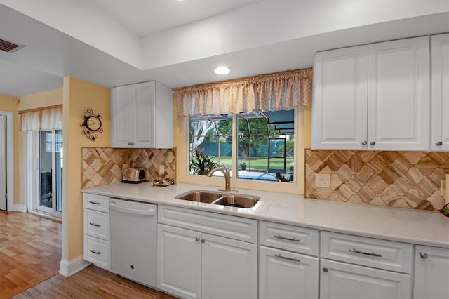 kitchen with white dishwasher, light hardwood / wood-style floors, sink, and white cabinets