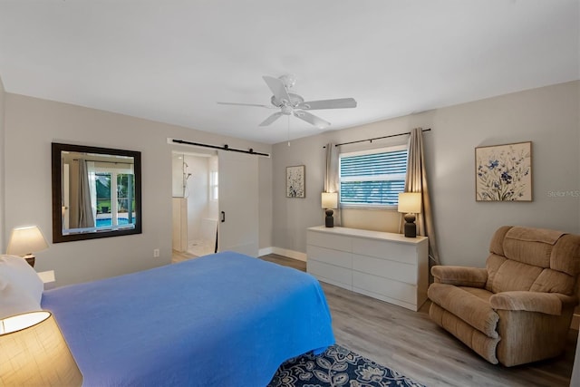 bedroom featuring light hardwood / wood-style flooring, a barn door, and ceiling fan