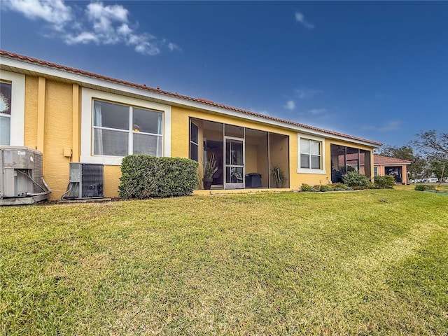 rear view of house with a yard, central AC unit, and a sunroom