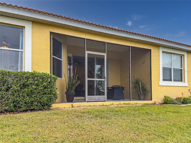 rear view of property featuring a lawn and a sunroom