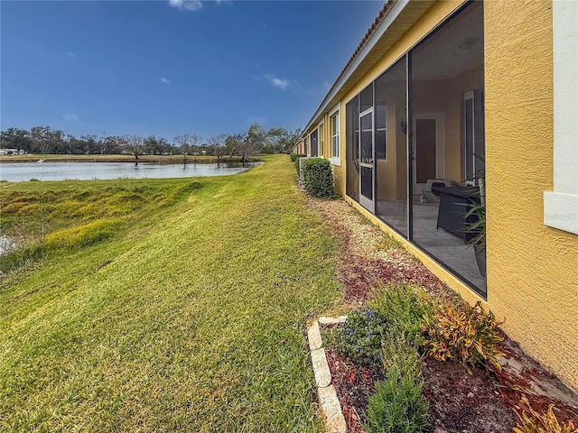 view of yard featuring a water view and a sunroom