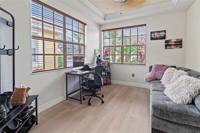 office area with ornamental molding, a raised ceiling, and light wood-type flooring