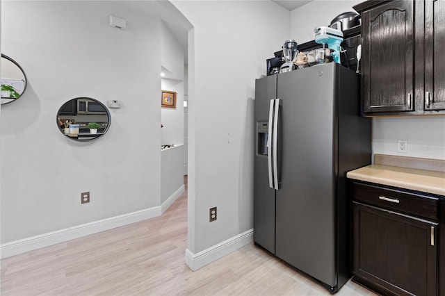 kitchen with dark brown cabinetry, stainless steel fridge, and light hardwood / wood-style floors