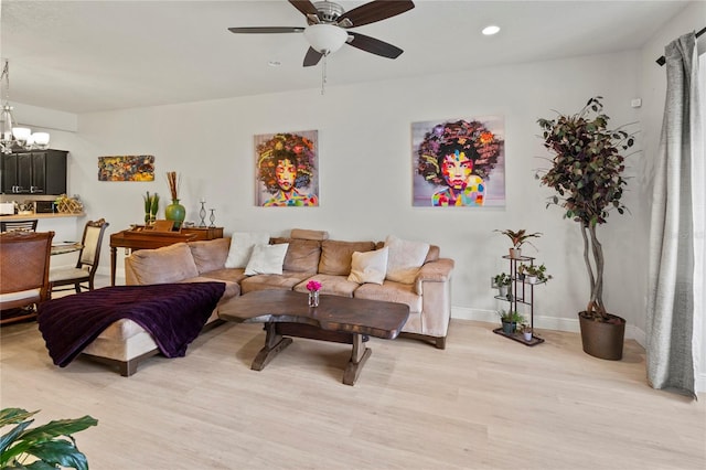 living room featuring ceiling fan with notable chandelier and light hardwood / wood-style floors