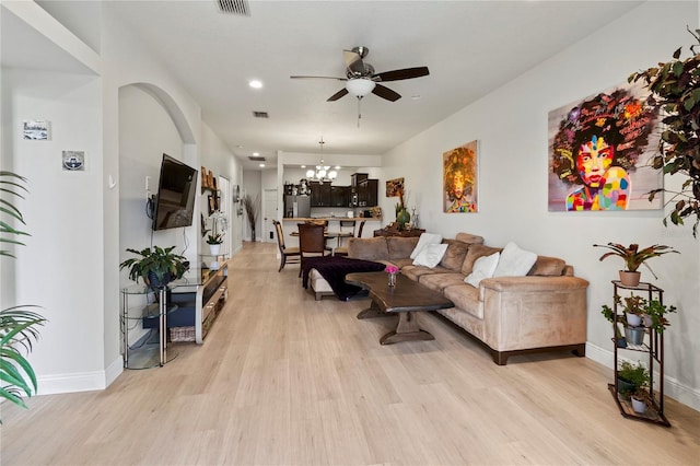 living room with ceiling fan with notable chandelier and light wood-type flooring