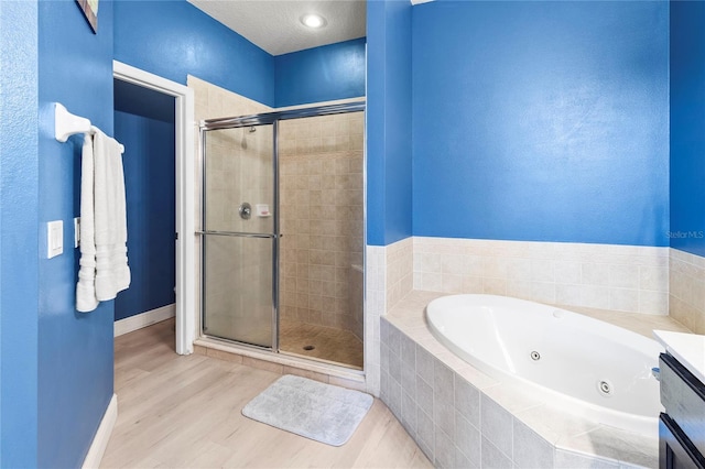 bathroom with plus walk in shower, hardwood / wood-style floors, and vanity