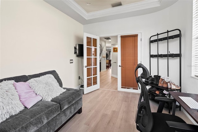 home office featuring french doors, ornamental molding, a tray ceiling, and light hardwood / wood-style flooring