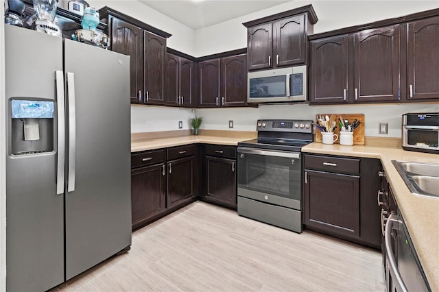 kitchen with dark brown cabinetry, appliances with stainless steel finishes, sink, and light wood-type flooring