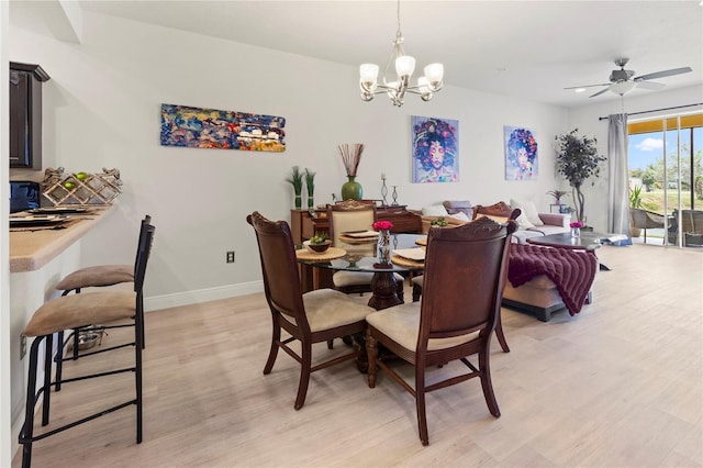 dining room with ceiling fan with notable chandelier and light hardwood / wood-style floors