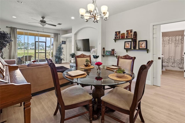 dining space with ceiling fan with notable chandelier and light hardwood / wood-style floors