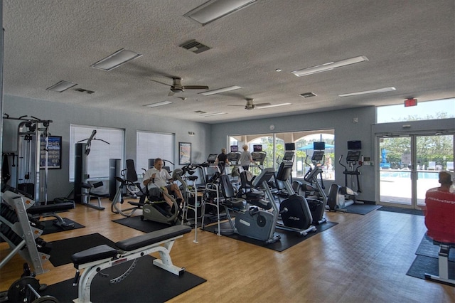 exercise room featuring wood-type flooring, ceiling fan, and a textured ceiling