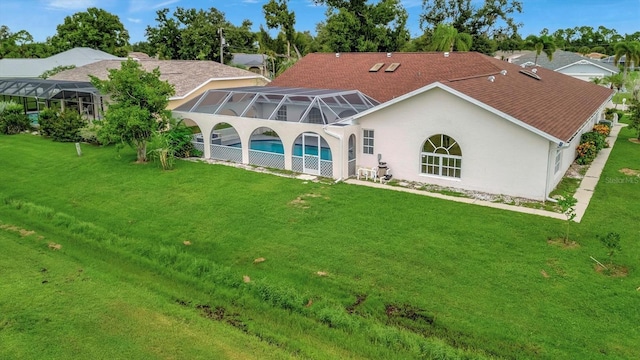 back of property with a yard and glass enclosure