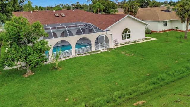 rear view of house featuring a lanai and a lawn