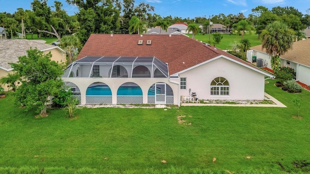 rear view of house with a yard and a lanai