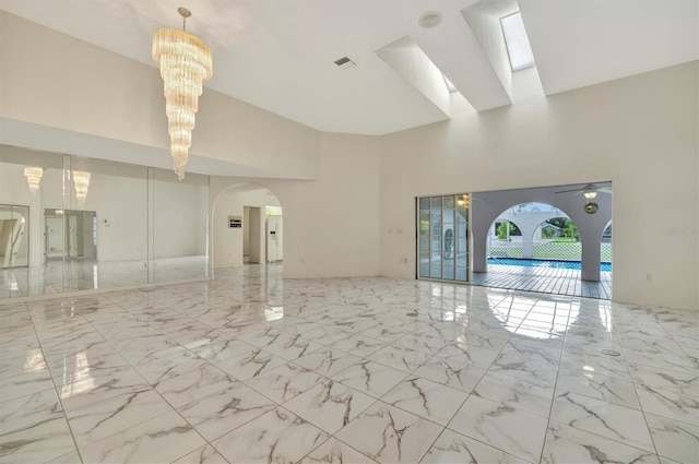 interior space featuring a towering ceiling and ceiling fan with notable chandelier