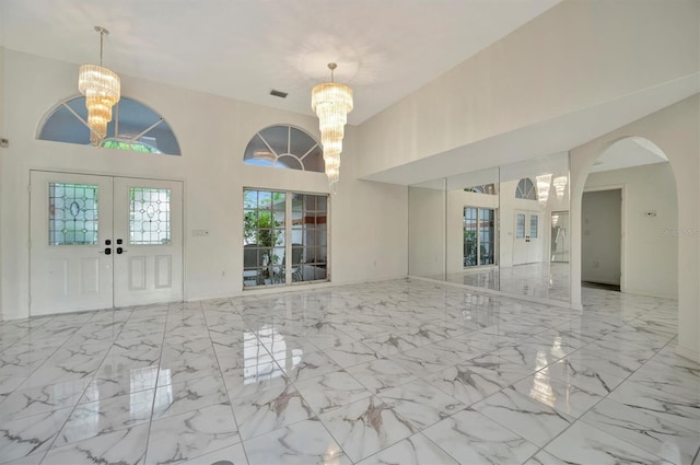 entrance foyer with a towering ceiling, an inviting chandelier, and french doors