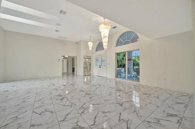 unfurnished living room with a skylight, a chandelier, and a high ceiling