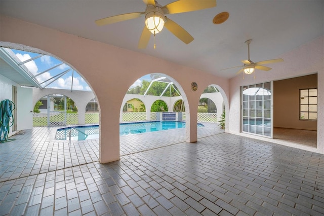 view of swimming pool with ceiling fan, glass enclosure, and a patio area