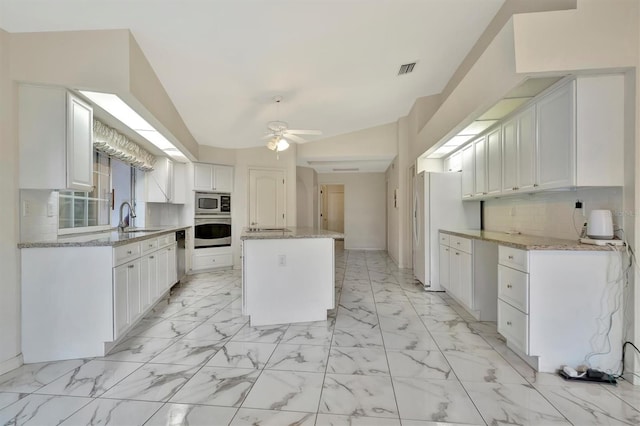 kitchen featuring sink, stainless steel appliances, tasteful backsplash, white cabinets, and a kitchen island