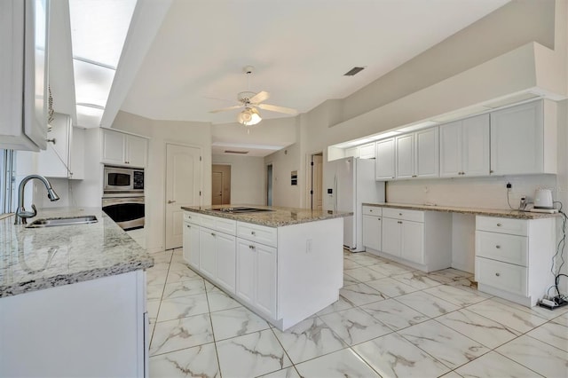 kitchen with sink, stainless steel appliances, tasteful backsplash, light stone countertops, and white cabinets