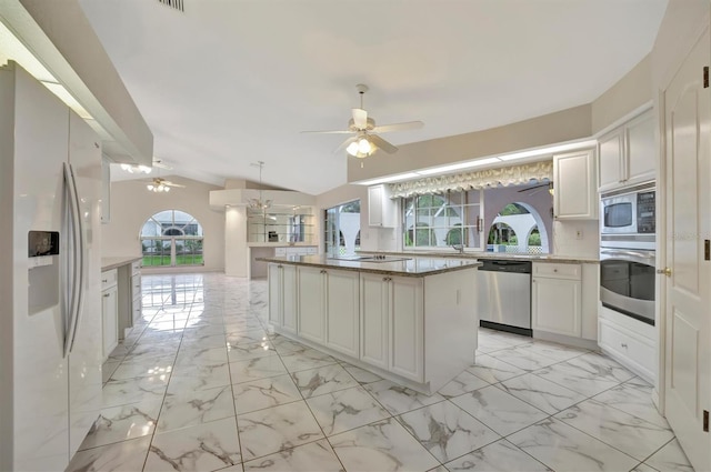 kitchen with a kitchen island, appliances with stainless steel finishes, tasteful backsplash, lofted ceiling, and hanging light fixtures