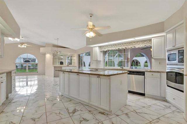 kitchen with vaulted ceiling, a kitchen island, appliances with stainless steel finishes, white cabinetry, and decorative backsplash