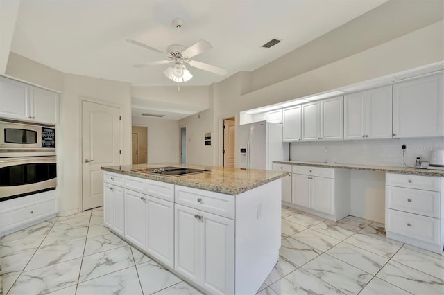 kitchen with white cabinetry, light stone counters, stainless steel appliances, and a center island