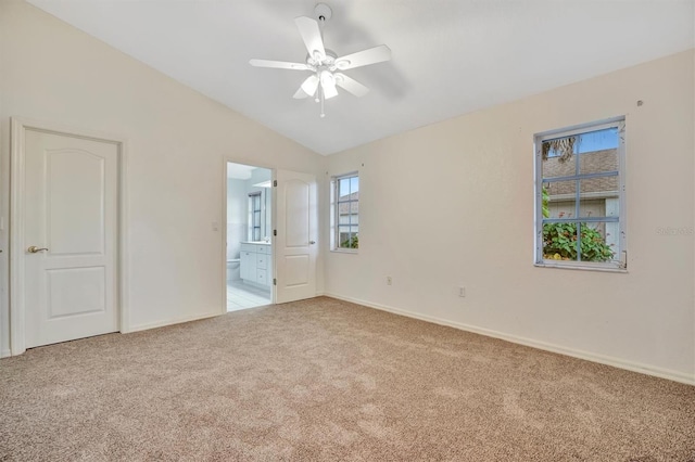 unfurnished bedroom with ceiling fan, lofted ceiling, ensuite bath, and light carpet