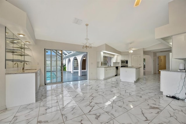 kitchen with sink, ceiling fan with notable chandelier, white cabinetry, stainless steel appliances, and decorative light fixtures