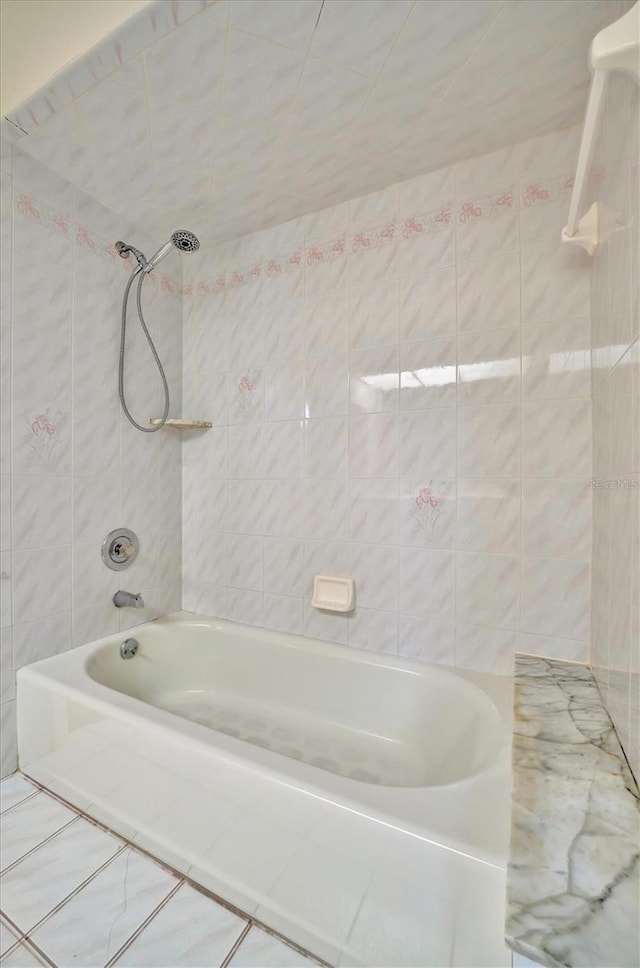 bathroom with tile walls, tile patterned floors, and tiled shower / bath