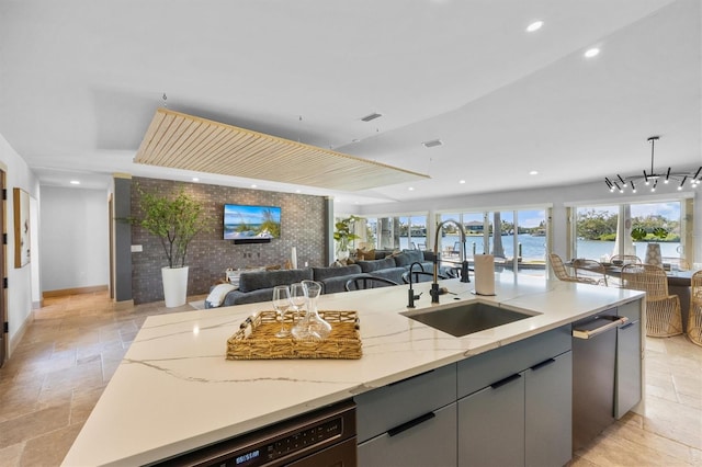 kitchen featuring gray cabinets, brick wall, dishwasher, sink, and light stone counters