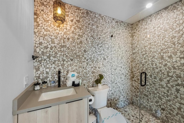 bathroom featuring vanity, a shower with door, and toilet